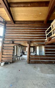 Interior of a log cabin under construction, showcasing exposed wooden beams