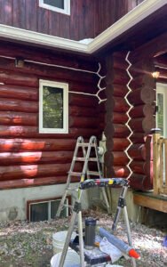 Log cabin exterior maintenance with ladders and tools