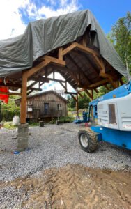 Wooden structure under construction with tarp cover and equipment onsite