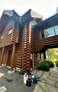 Two-story wooden log house with garage in picturesque setting