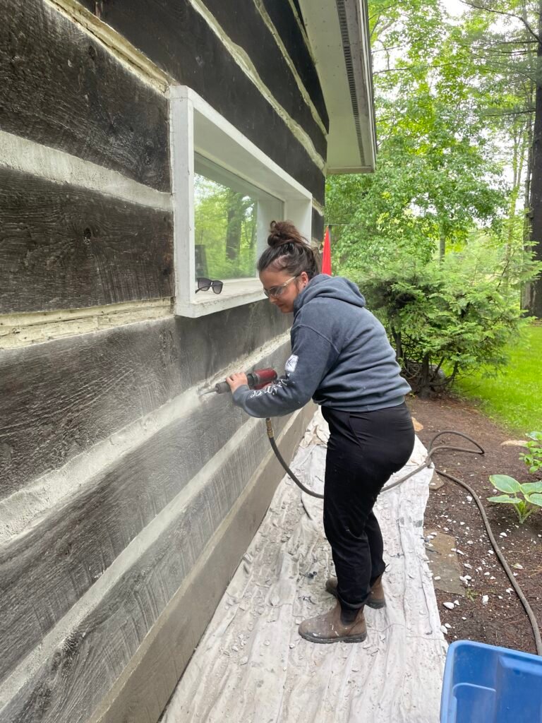 Person sanding wood on vintage building exterior