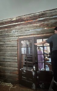 Person measuring window frame in rustic log cabin interior