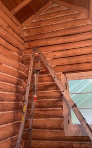Log cabin interior under renovation with a ladder and caulking gun