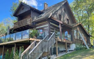 Rustic wooden house with glass deck railing in a serene setting