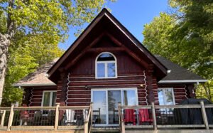 Log cabin exterior with large windows in a wooded setting