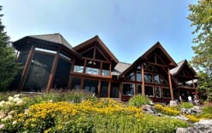 Modern log home with large windows and surrounding garden