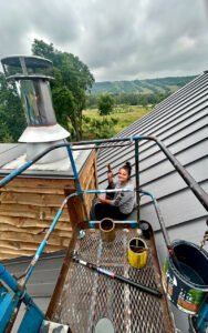 Woman painting rooftop chimney on a rural farm setting