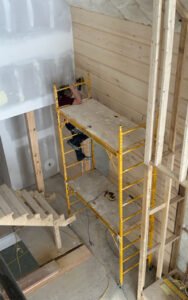Worker installing wooden wall panels on scaffolding