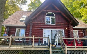 Rustic Canadian log cabin with large deck and surrounded by trees
