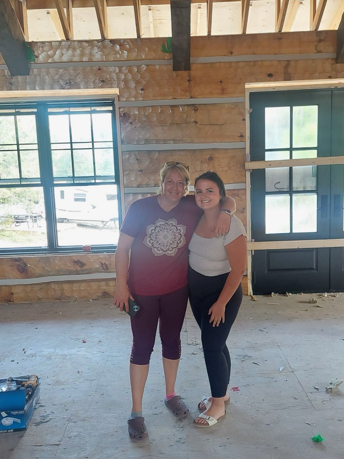 Two women standing in a partially renovated home interior