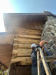 Person restores rustic log cabin exterior in Muskoka