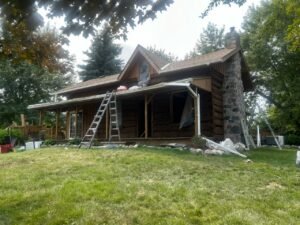 Rustic log cabin with renovation tools in a lush green yard