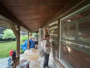 Workers renovating a wooden porch of a rustic house