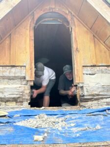 Restoration work on historic log house attic by two men