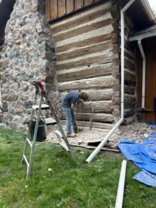 Man restoring historic log building exterior