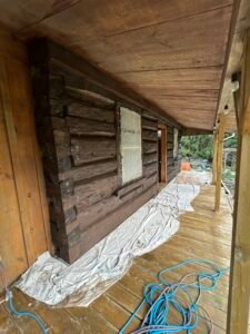 Log cabin renovation with wooden deck and tarps