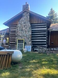 Restoration of a historic log cabin with stone chimney