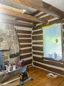 Rustic log cabin interior renovation with stone fireplace