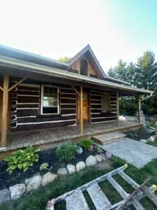 Restored wooden log cabin with porch and garden in rural Canada