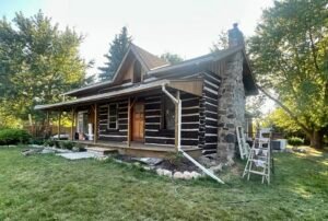 Restored log cabin with chimney in a lush green setting