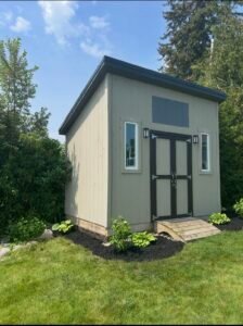 Modern garden shed with gable roof and surrounding greenery
